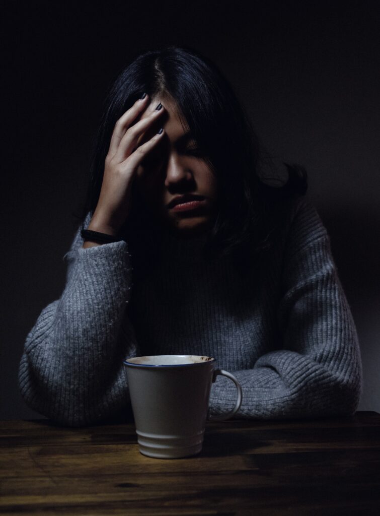 Image of a woman sitting at a table looking upset. What is functional medicine? How can it help with your chronic disease In Orland Park, IL 60448? At Anchored In Health our functional medicine doctor can help answer those questions in the Chicago area 60462. Contact us today! 