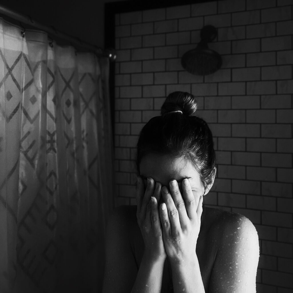 Black & white image of a woman in a bathroom appearing upset. Functional medicine uses shape reclaimed and homeopathic medicine to reduce stress symptoms in Orland Park, IL 60487. You can get relief with the help of a functional medicine doctor in Orland Park, IL 60439.