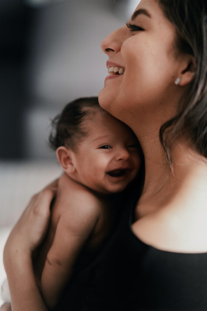 Image of a mom holding her new baby and smiling. Have you heard of a post natal massage? You can get "massage therapy near me" to support your recovery after birth with a massage therapist. Experience the benefits of a postpartum massage in Orland Park, IL 60449. Reach out now!
