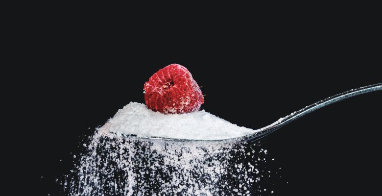 Image of sugar on a spoon topped with a raspberry. Showing one of the causes of diabetes that a functional medicine doctor in Orland Park & Chicago, will help address. Changing eating habits is one of the natural remedies for diabetes.
