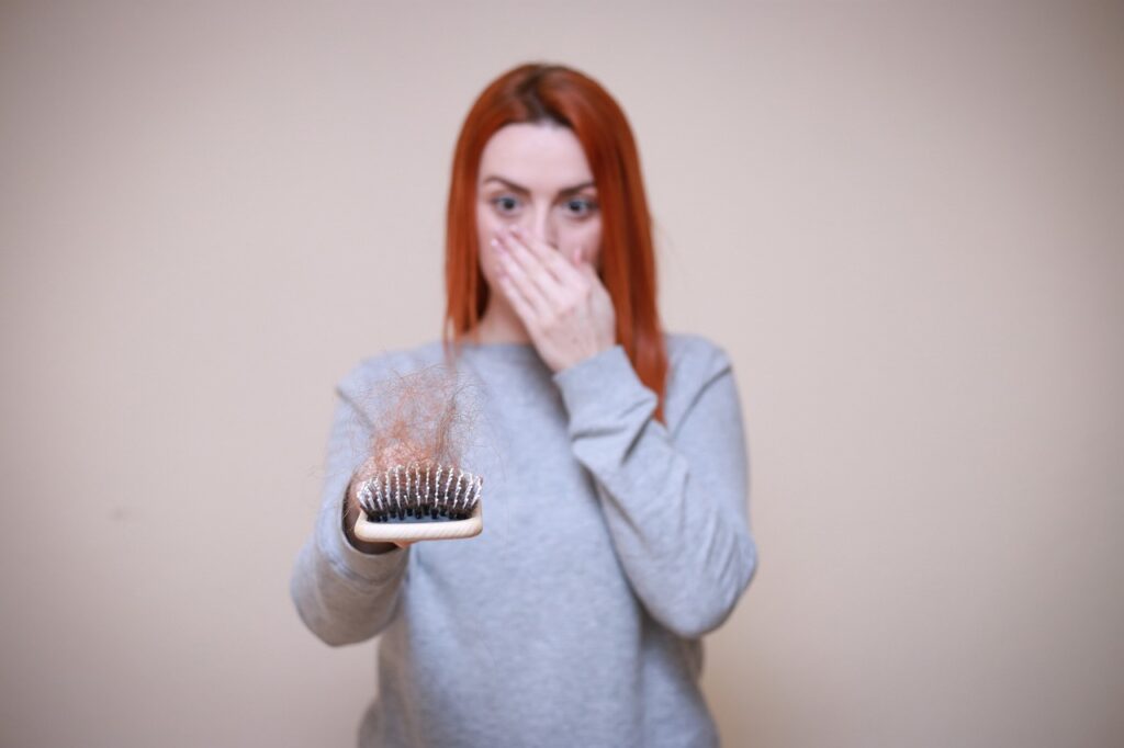 A woman holds a hand over her mouth while holding a hair-filled brush. Learn more about the support a functional medicine doctor in Orland Park, IL can offer by searching “hormone imbalance Orland Park, IL”  today. A holistic doctor in Orland Park, IL can offer support today.