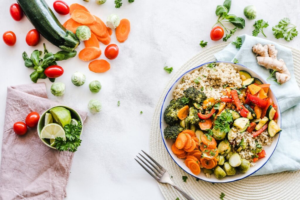 A top down view of salad on a table next to vegetables. This can represent a change in diet that a functional medicine doctor in Orland Park, IL can help you navigate. Contact a functional medicine doctor in the Chicago area today for more support. 
