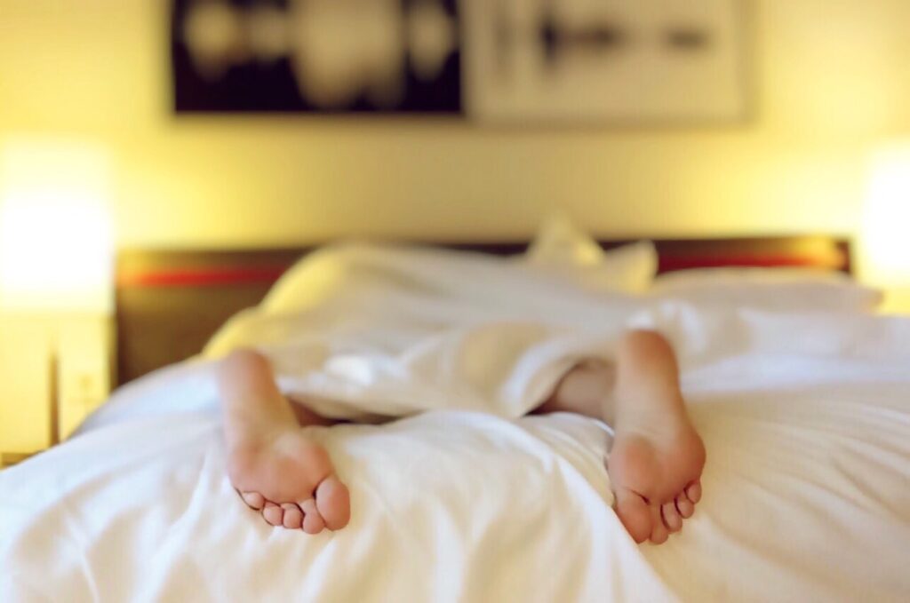 A close up of feet peaking out from a bed. Learn more about the support a functional medicine doctor in Orland Park, IL can offer by searching “what is functional medicine Chicago are” today. 
