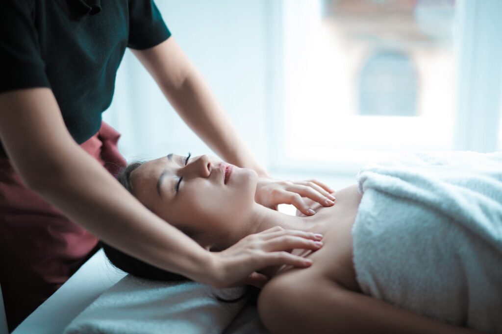 A person massages the shoulders of a woman laying on a bed. This could represent the benefits of receiving a therapeutic massage in Orland Park, IL. Learn more about massage therapy in Orland Park, IL by searching “therapeutic massage near me” today.
