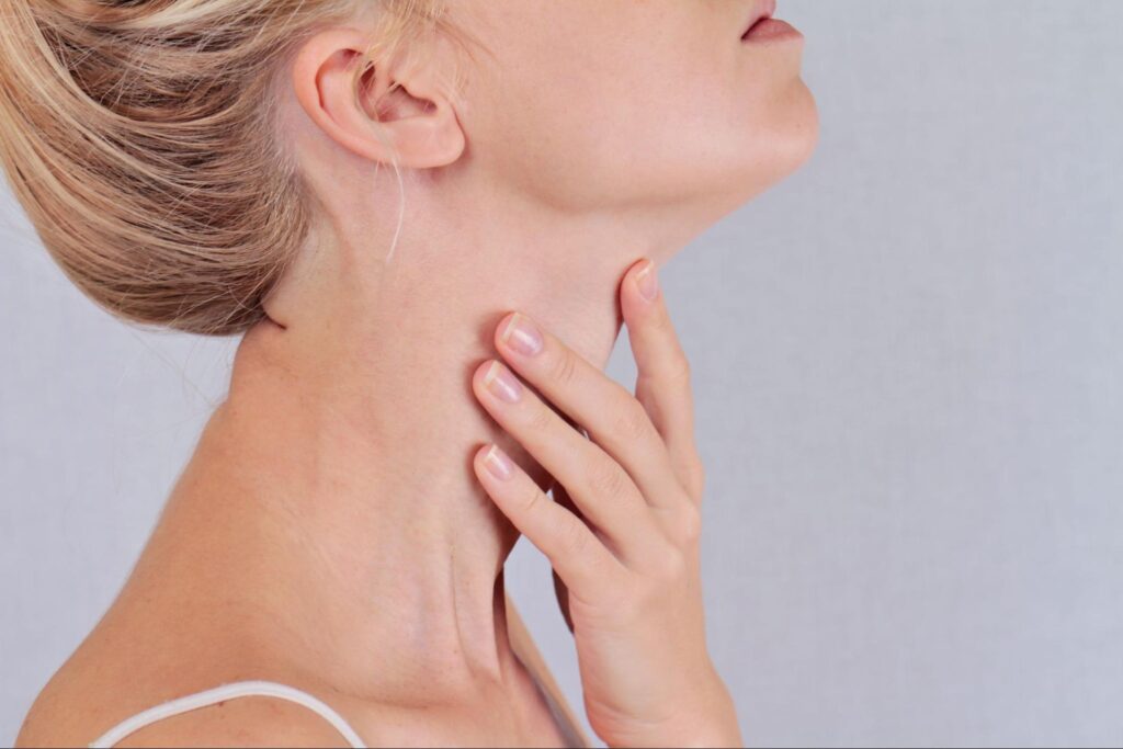 A close up of a woman touching her throat. This could represent thyroid pain a holistic doctor in Orland Park, IL can help you overcome. Learn more about hormone imbalance Orland Park, IL today.
