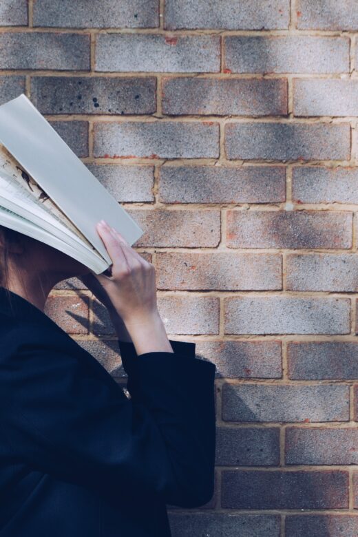 A woman covers her face with a book. This could represent thyroid pain a holistic doctor in Orland Park, IL can help you overcome. Learn more about hormone imbalance Orland Park, IL today.
