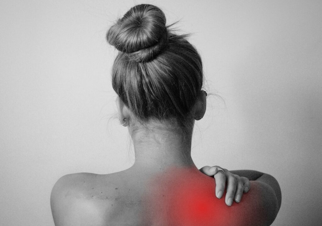 A woman holds her shoulder while facing away from the camera. This could represent chronic pain and how massage therapy in Orland Park, IL can help cope with symptoms. Contact a massage therapist in Orland Park, IL or search for massage therapy near me.
