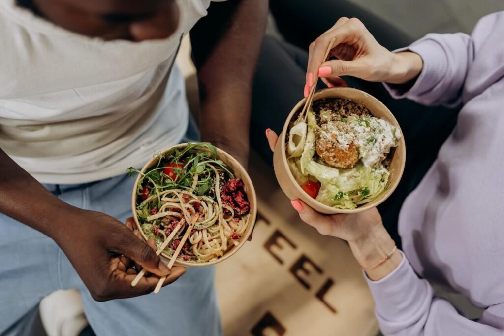 A close up of two people enjoying noodles while talking. Learn how dietary changes learned from a holistic doctor in Orland Park, IL can offer support. Search for what is functional medicine Chicago area for support. 
