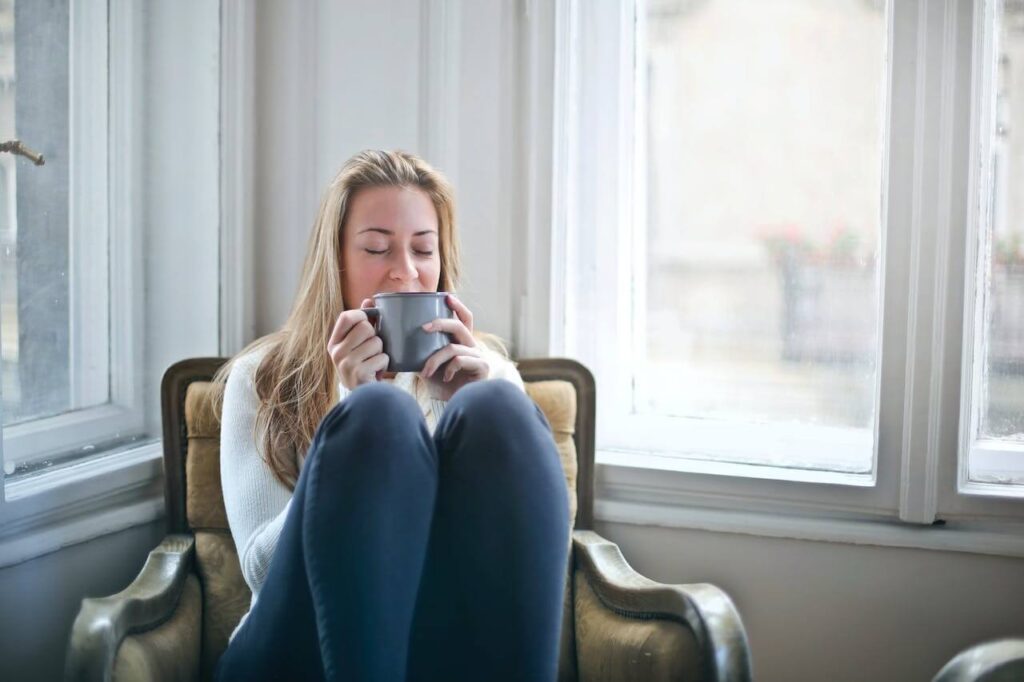 A woman enjoys a drink while sitting in a chair next to a window. Learn more about the help a holistic doctor in Orland Park, IL can offer support with genetic health testing in the Chicago area and more. 
