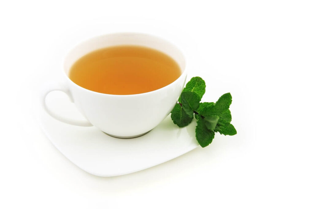 A cup of green tea rests on a saucer next to a garnish. Learn how tea can help with hormonal weight gain in Orland Park, IL. Search for a holistic doctor for answers to questions like "what is functional medicine Chicago area" today. 
