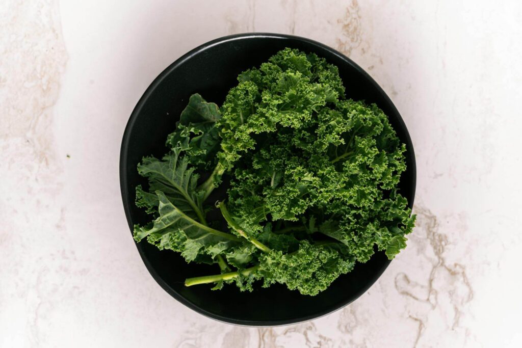 A top down close up of leafy greens in a bowl on a marble counter. Learn how certain foods can help with detoxification in Orland Park, IL. Search for functional medicine in Orland Park, IL or contact a holistic doctor in Orland Park, IL for help. 
