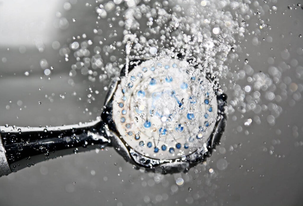 A close up of an active shower head representing the help showering can offer after a lymphatic drainage massage in Orland Park, IL. Learn more about the help a holistic doctor in Orland Park, IL can offer by searching for a therapeutic massage near me. 
