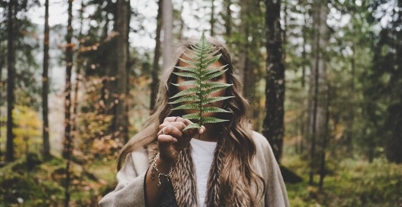 A woman holds a plant in front of her face, obstructing it from the camera. This could represent a natural remedy for inflammation that a holistic doctor in orland park, il can help you realize. Learn more about the help holistic massage in Orland Park, IL can offer by searching for an acupuncturist in the Chicago area.