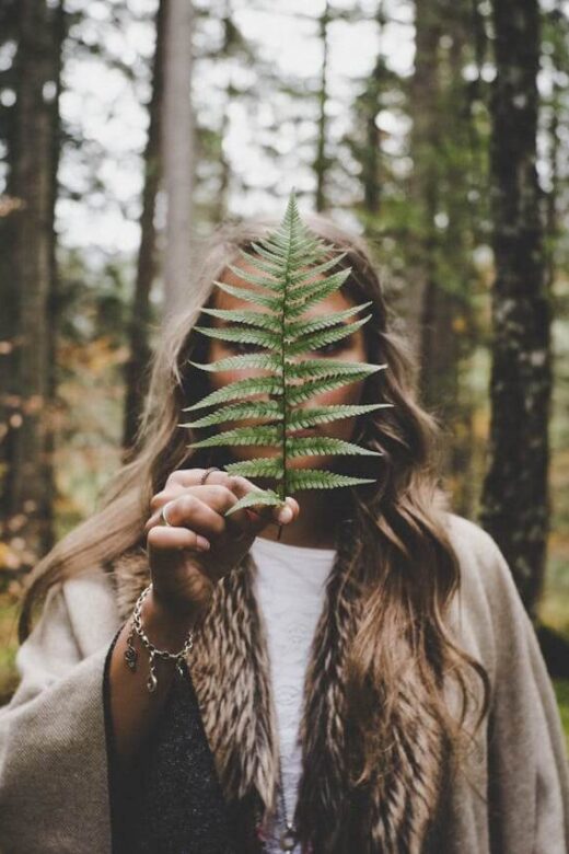 A woman holds a plant in front of her face, obstructing it from the camera. This could represent a natural remedy for inflammation that a holistic doctor in orland park, il can help you realize. Learn more about the help holistic massage in Orland Park, IL can offer by searching for an acupuncturist in the Chicago area.