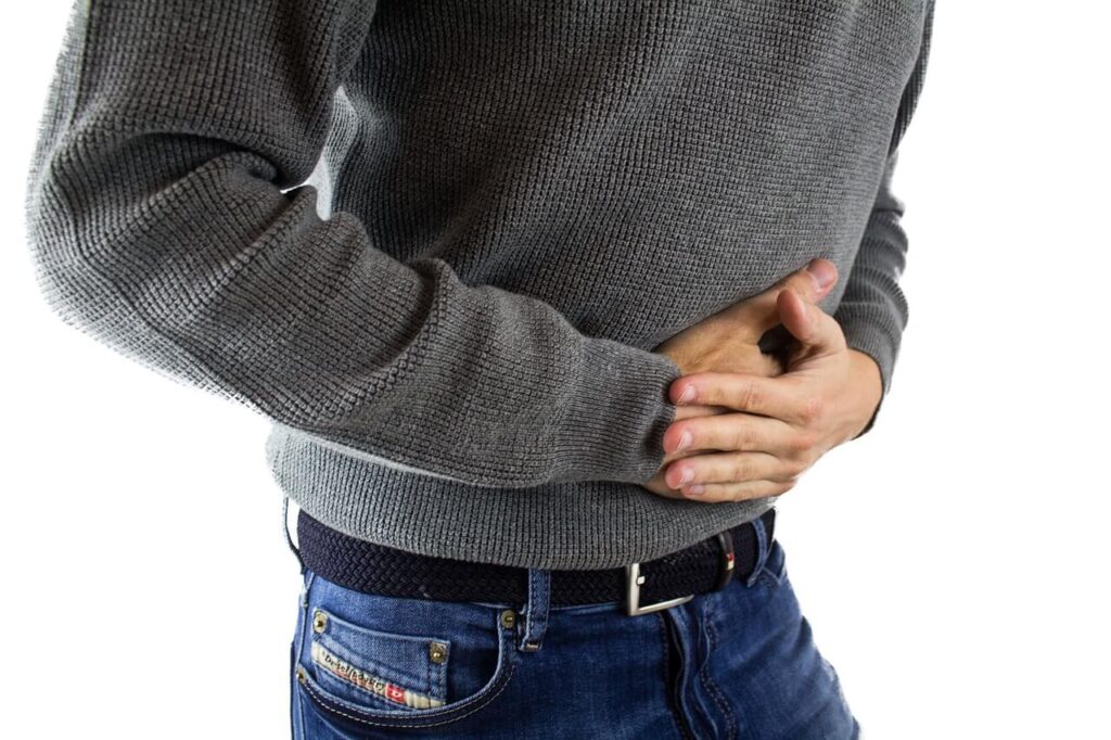 A close up of a person holding their stomach in pain. This could represent the need to find natural remedies for constipation in Orland Park, IL. Search for an acupuncturist in Orland Park, IL to learn more about holistic acupuncture Orland Park, IL and more. 
