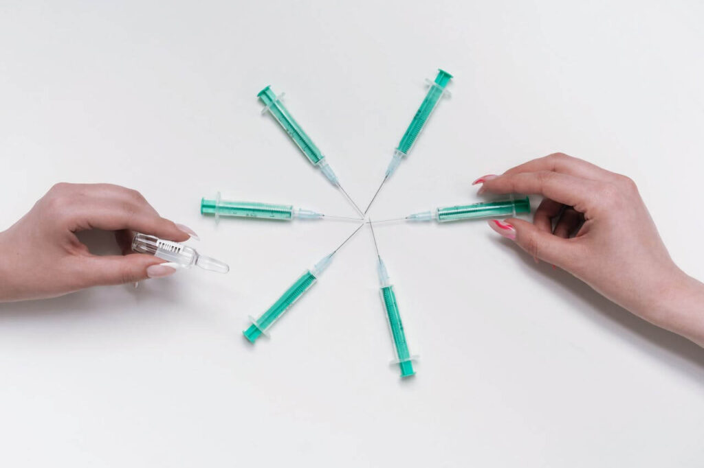 A top down view of six GLP-1 needles as hands adjust them. This could represent the stress of using weight loss drugs that a holistic doctor in Orland Park, IL can address. Learn more about the standard American diet and how a weight loss program in Orland Park, IL can help you today.
