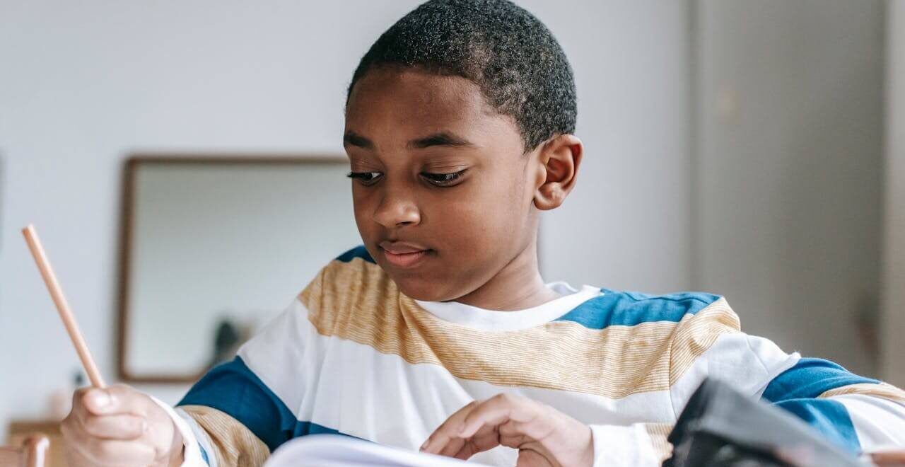 A child smiles while studying and writing in a notebook. Learn more about overcoming stress during academic stress by contacting a massage therapist in Orland Park, IL. Learn more about a therapeutic massage in Orland Park, IL by searching for "therapeutic massage near me" today.