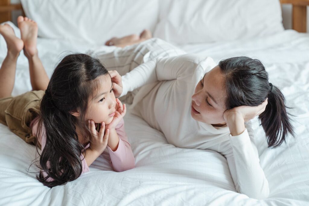 A mother and child lay on a bed while having a conversation. Learn more about overcoming stress during academic stress by contacting a massage therapist in Orland Park, IL. Learn more about a therapeutic massage in Orland Park, IL by searching for "therapeutic massage near me" today. 
