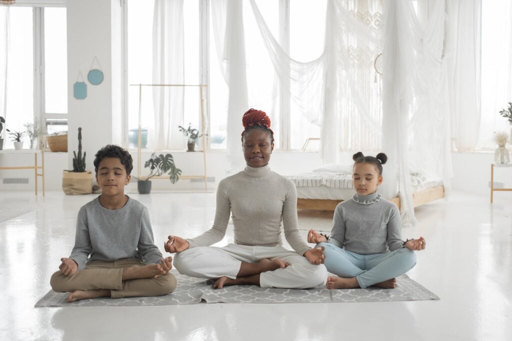 A mother sits on a mat in a meditative pose with her children sitting on either side of her. Learn how about how a massage therapist in Orland Park, IL can offer support with massage therapy in Orland Park, IL and other services. Search for a therapeutic massage in Orland Park, IL to learn more.
