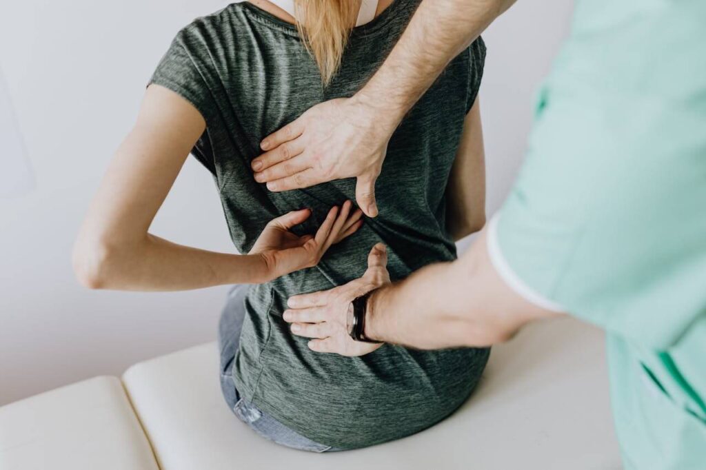 A person tries to identify the source of back pain on a patient. This could symbolize the support a holistic chiropractor in the Chicago area can offer. Learn more about chiropractic care for sciatica in Orland Park, IL. Search for "chiropractor Orland Park" today. 
