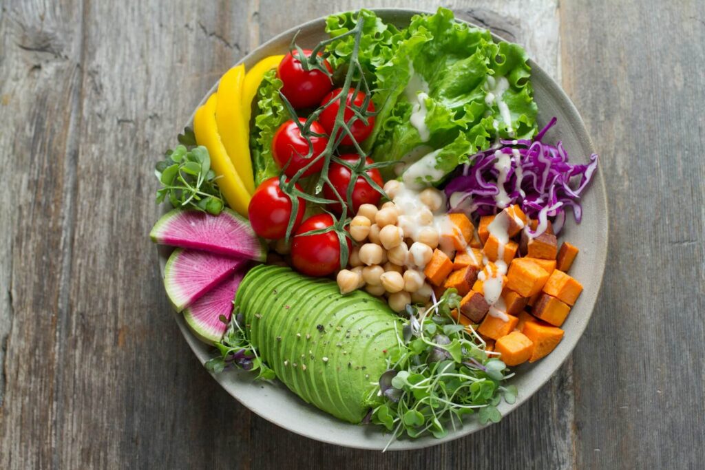 A top down view of a plate filled with healthy foods including avocado, carrot, chick peas, and tomatoes. Learn more about the benefits of functional medicine in Orland Park, IL and search for how a functional medicine doctor in Orland Park, IL can offer support. Search for holistic medicine in the Chicago area for more support.  
