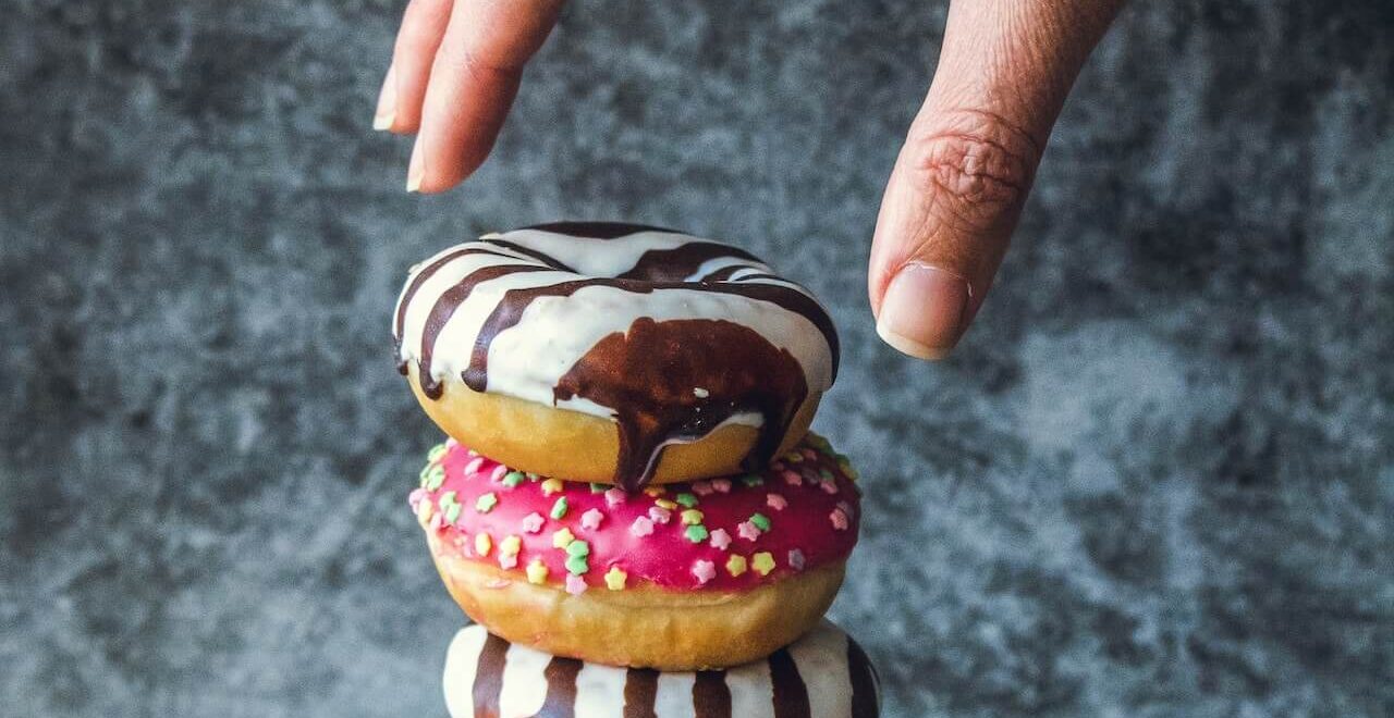 A close up of hands reaching toward a stack of doughnuts. Contact a functional medicine doctor in the Chicago area to learn more about answers like "what is functional medicine Chicago area". Search for functional medicine in Orland Park, IL and how holistic medicine in the Chicago area today.