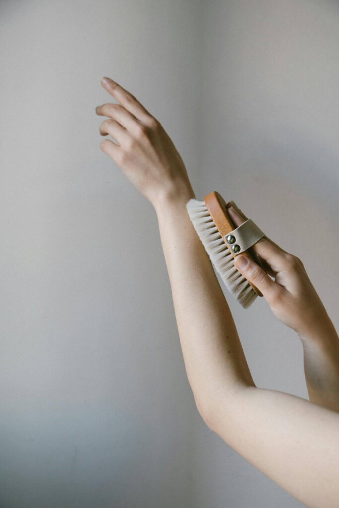 A person holds their arm up while dry brushing their arm. Learn more about about holistic solutions for detoxification in Orland Park, IL by searching for Shape reclaimed in the Chicago area and how holistic medicine in the Chicago area can help today. 
