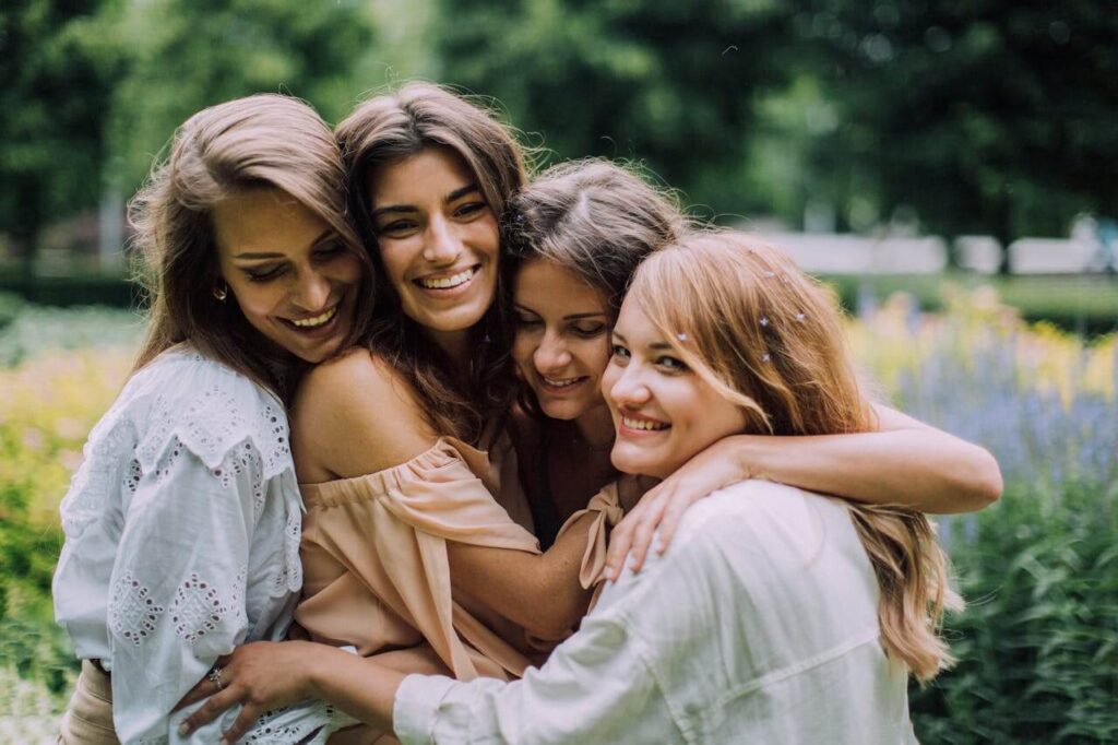 A group of four young women is embracing each other in a warm hug outdoors, surrounded by lush greenery and flowers. Did you know hugs can actually stimulate oxytocin? Learn more about how a therapeutic massage in Orland Park, IL and how a holistic doctor in Orland Park, IL can help today.
