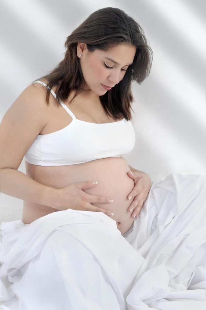 Maternity Photos | chiropractic care in orland park, il | functional medicine doctor in the chicago area | holistic chiropractor in the chicago area | holistic doctor in chicago, il | Orland Woods | Park Station Boulevard area | Lincoln Park Shows a pregnant woman holding her belly while posing for a maternity shoot. Represents how pregnancy can be tough on our birthing people's bodies and how a holistic doctor in chicago, il providing chiropractic care in orland park, il can really support you.