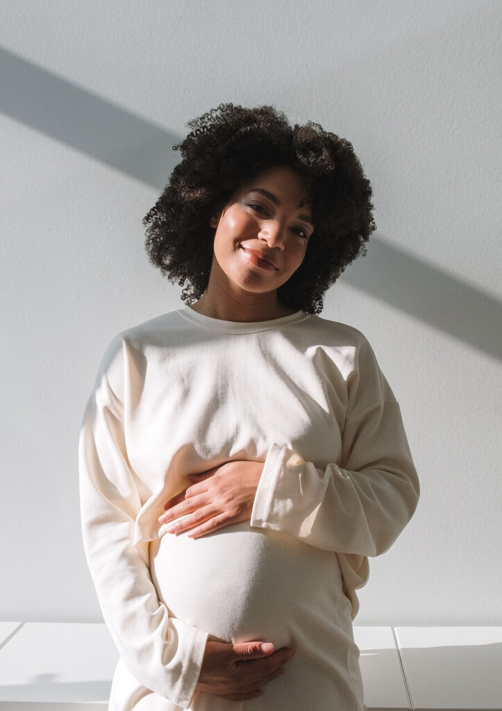 Happily Pregnant | holistic chiropractor in the chicago area | functional medicine doctor in the chicago area | holistic doctor in chicago, il | chiropractic care in orland park, il | West Loop | Southport Corridor | Hyde Park Shows a smiling mother to be holding her pregnant stomach. Represents how a functional medicine doctor in the chicago area who is also a holistic chiropractor in the chicago area can support you throughout your pregnancy.