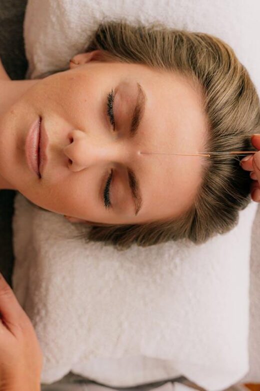 Shows a woman laying on a pillow with an acupuncturist in Orland Park, IL standing here. Represents how acupuncture in Orland Park, IL can support you on your fertility journey.
