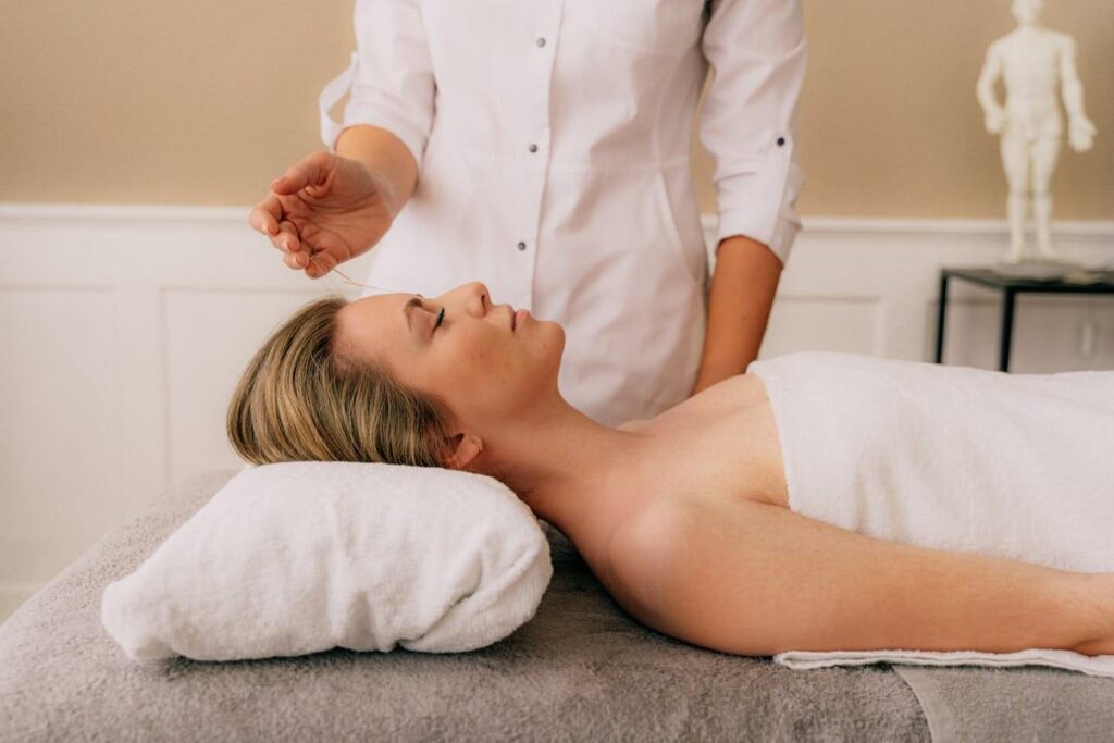 Shows a woman laying on a table readying herself for acupuncture. Represents how an acupuncturist in the chicago area who is also a holistic doctor in chicago, il will support you in fertility treatments.