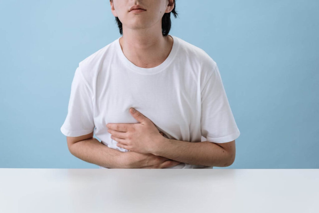 Stomach Problems | functional medicine in orland park, il | functional medicine doctor in the chicago area | functional medicine doctor in orland park, il | holistic doctor in chicago, il | Crystal Tree, IL | Orland Woods, IL | Streeterville, IL Shows a young person wearing a white shirt and holding their stomach. Represents how a holistic doctor in chicago, il can support you with a leaky gut by using functional medicine in orland park, il