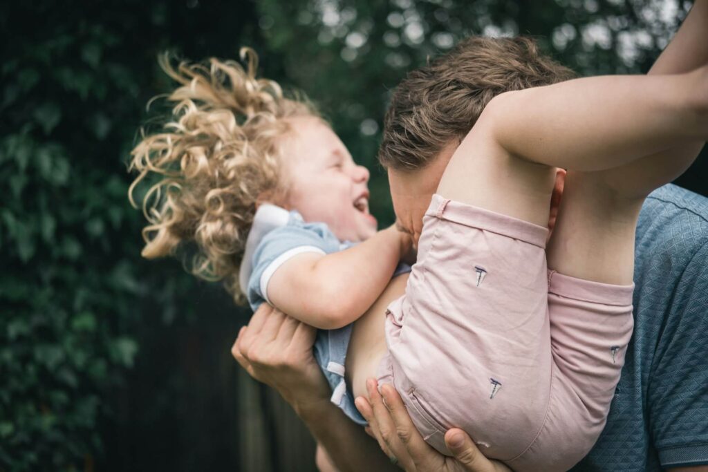 Shows a child laughing as their parent is blowing on their stomach. Represents how partnering with a chiropractor orland park to provide chiropractic care in orland park, il to your child.