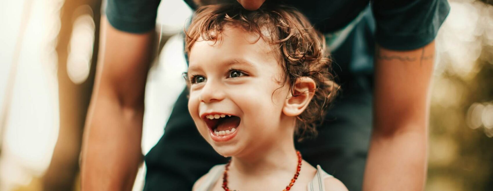 Shows a child with a big smile with their parent kissing their head. Represents how a chiropractor orland park or a holistic chiropractor in the chicago area can help your child while they grow.