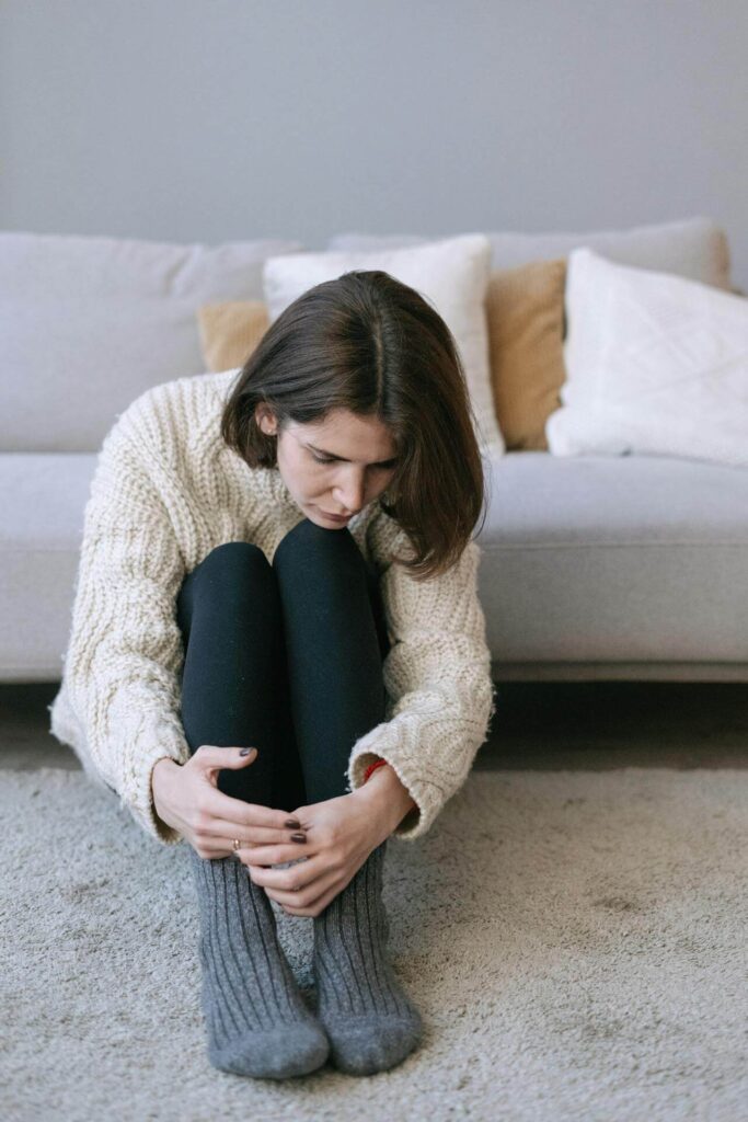 Woman hugging her knees while sitting on the floor. Represents how researching what what is functional medicine in orland park can lead you to functional medicine and an acupuncturist in orland park, il.