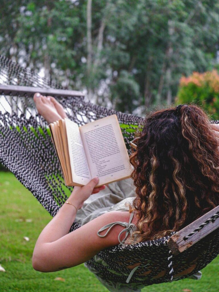 Woman relaxing in a hammock reading a book. Work with a functional medicine doctor in Orland Park, IL to navigate and heal from blood sugar issues related to stress.