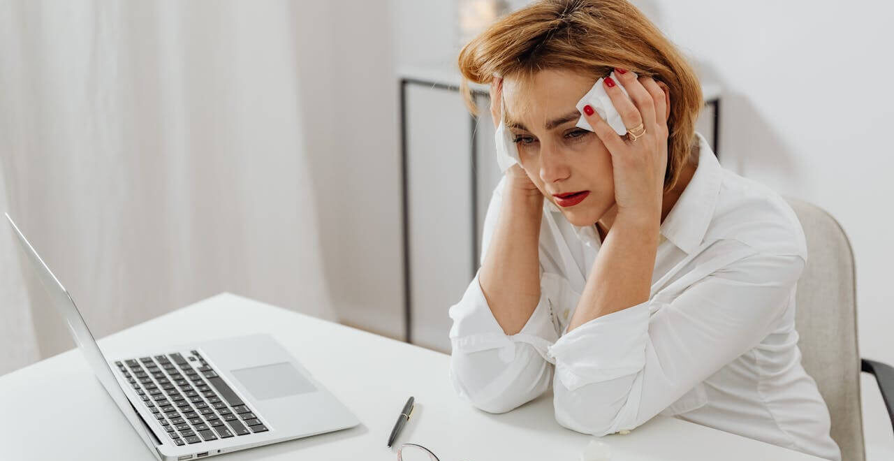 Stressed woman sitting at a desk holding her head. Find support in reducing your stress and lowering your blood sugar with functional medicine in Orland Park, IL.