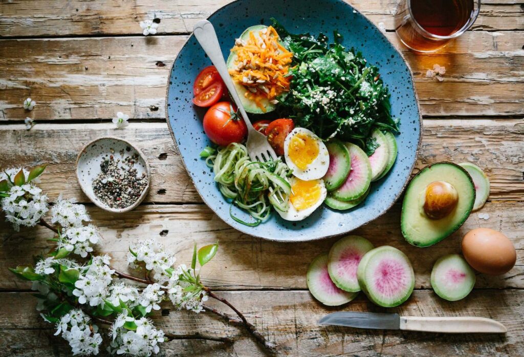 Bowl of colorful vegetables sitting on a wooden table. With the support of a functional medicine doctor in Orland Park, IL you can learn to take control of stress and your blood sugar in healthy ways!
