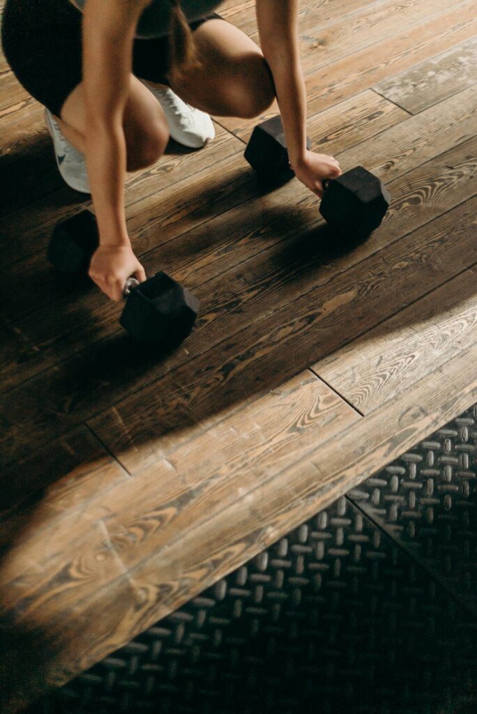 Woman placing her hands on weights on hard wood floor. With the help of a functional medicine doctor in Orland Park, IL you can begin to overcome perimenopause weight gain in healthy ways.