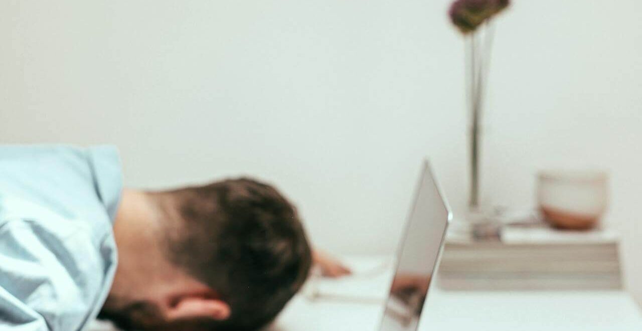 Tired man laying his head on his desk. If you struggle with stress and adrenal fatigue, work with a functional medicine doctor in Orland Park, IL to overcome your blood sugar issues.