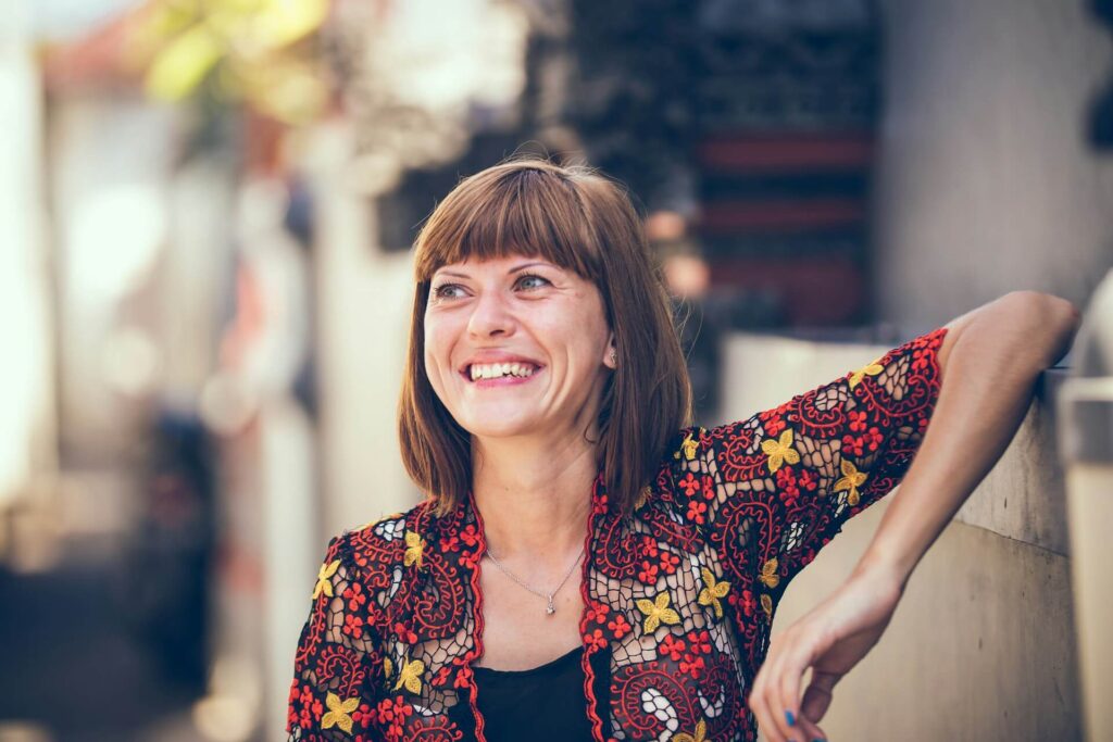 Smiling woman leaning her arm against a wall. If you're struggling for answers, discover how DUTCH testing in functional medicine in Orland Park, IL can help.