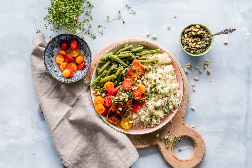 Bowls of colorful vegetables and lean protein sitting on a marble table with napkin. With the support of a functional medicine doctor in Orland Park, IL you can learn to take control of adrenal fatigue, healthy gut microbiome and balancing blood sugar in healthy ways!