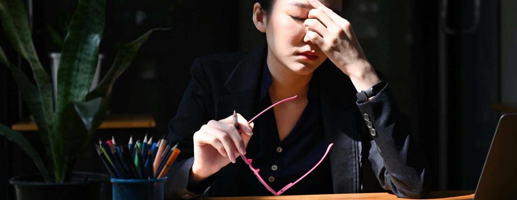 Stressed woman sitting at a desk pinching her eyes. Find support in reducing your stress and adrenal fatigue with functional medicine in Orland Park, IL.