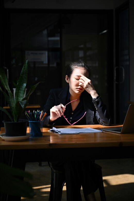 Stressed woman sitting at a desk pinching her eyes. Find support in reducing your stress and adrenal fatigue with functional medicine in Orland Park, IL.