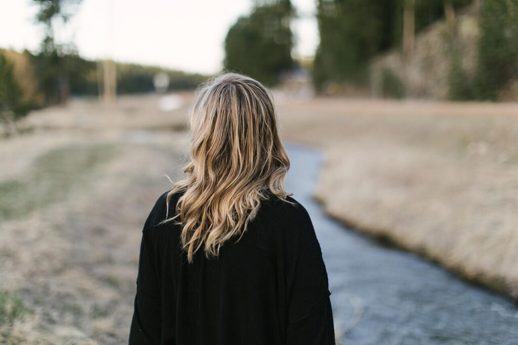 Woman wearing a black sweater walking on a path outside. A functional medicine doctor in Orland Park, IL helps patients reset an overactive stress response naturally.