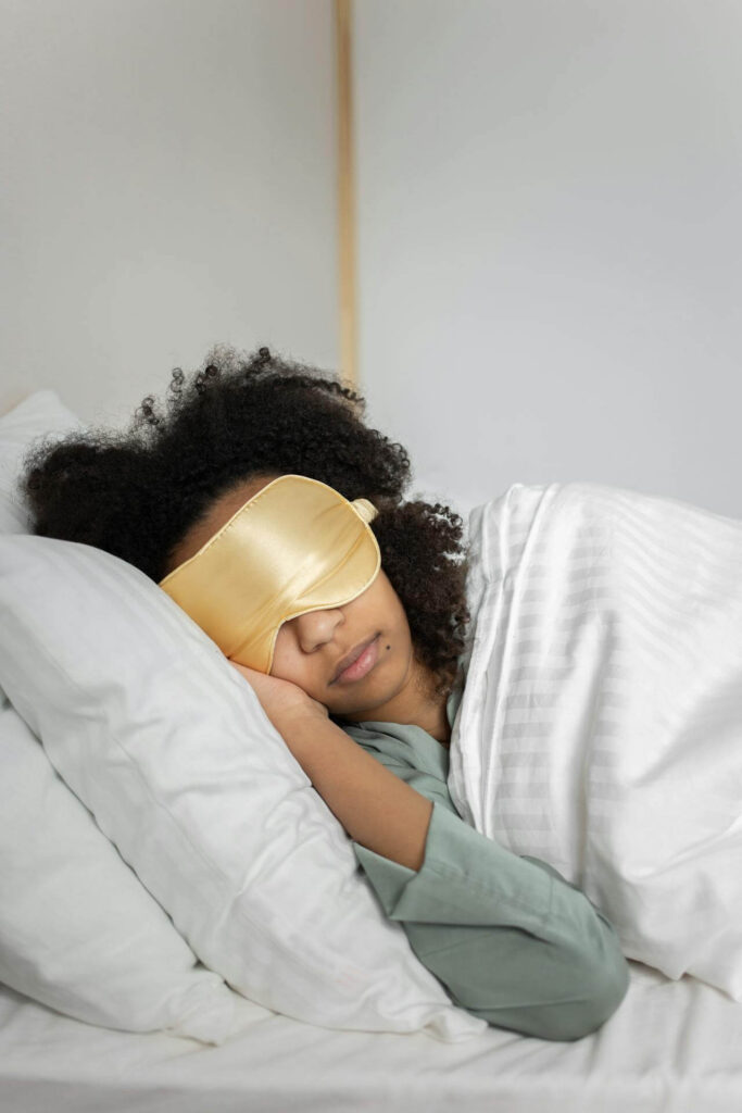 Woman laying in bed with a gold sleep mask. Discover root-cause relief from chronic stress through functional medicine in Orland Park, IL.