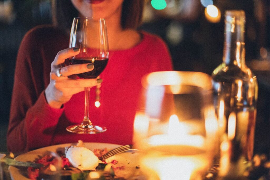 wine | functional medicine doctor in Orland Park, IL | functional medicine | blood sugar and mood | Homewood | Oak Lawn | Mokena Woman sitting at a dinner table holding a glass of wine. With the support of a functional medicine doctor in Orland Park, IL you can learn to avoid sleepiness after eating.