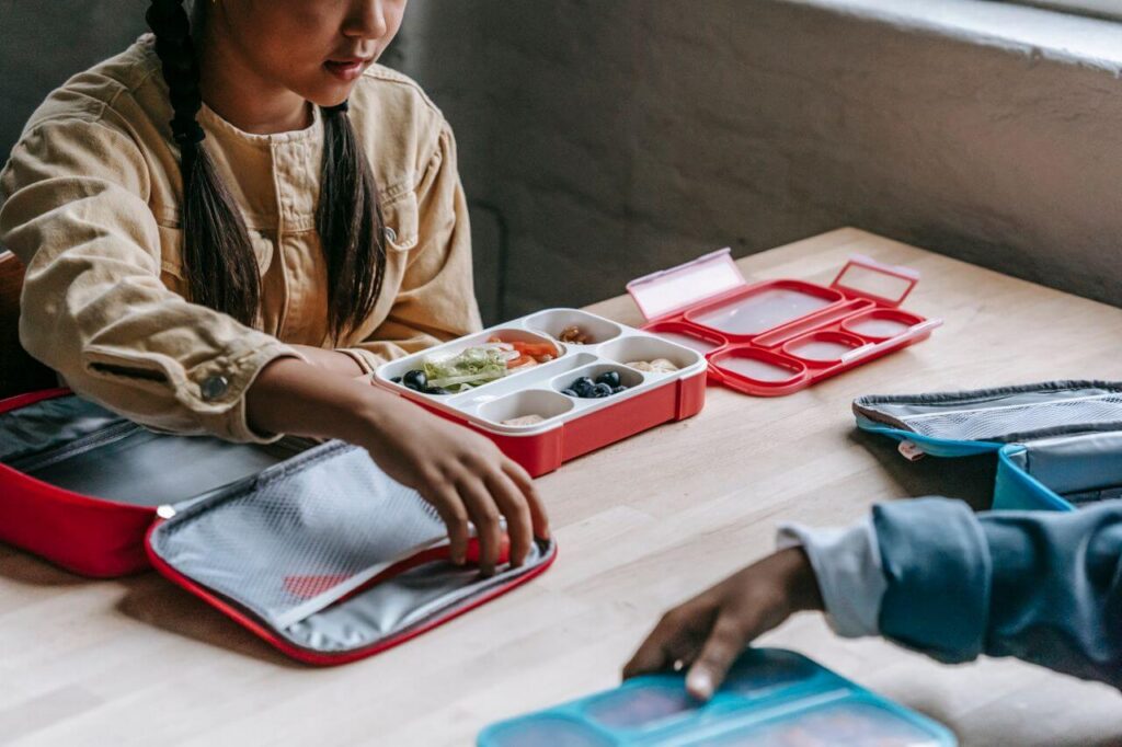 lunch | how to get a good night sleep | functional medicine sleep | functional medicine doctor | Oak Lawn | Orland Park | Homewood Two children sitting at a table opening their lunchboxes filled with food. Learn how to get a good night sleep this back-to-school season with sleep support tips from a functional medicine doctor in Orland Park, IL.
