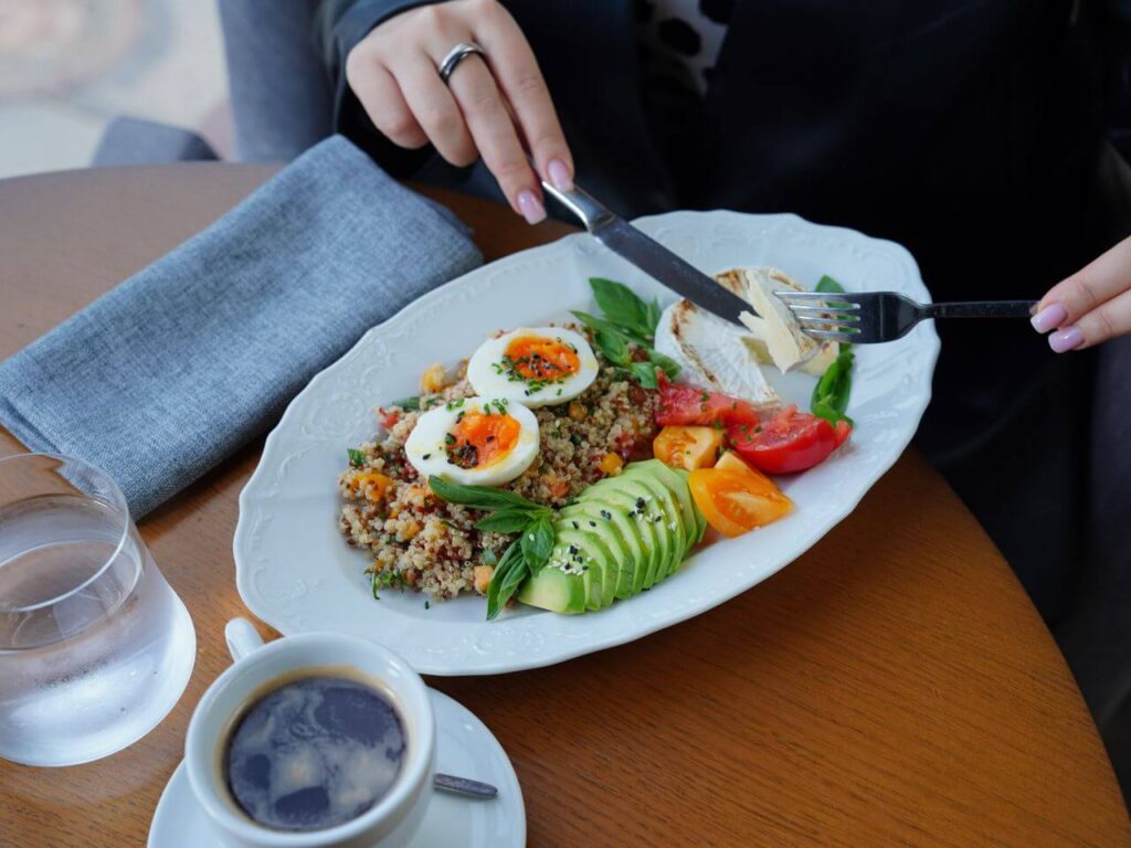 Plate of colorful foods with someone holding a knife and fork. Begin to manage your blood sugar and weight with Shape Reclaimed in Orland Park, IL.
